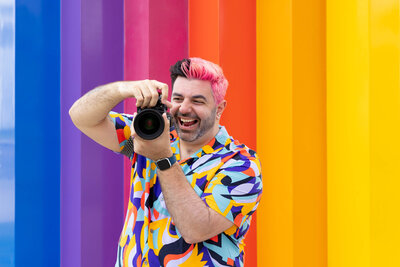 A photographer laughing as they hold up their camera.