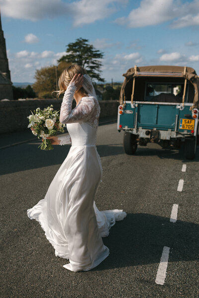 Bride's Sassi Holford Dress catches the breeze as she approaches the church 