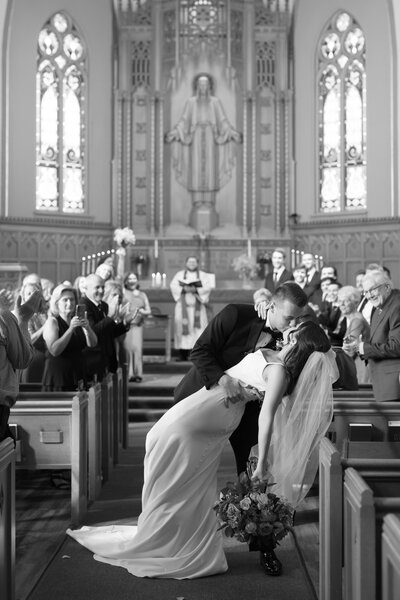 Groom kisses and dips bride down the aisle after being announced husband and wife while guests cheer based in Springfield Illinois and taken by Lacey Graham Photography