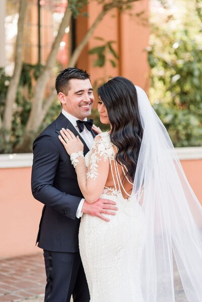 Bride and groom embracing as groom smiles fondly at bride