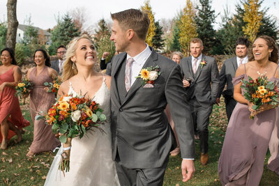 Bridal party walks with bride and groom on beautiful fall day