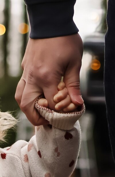 Twee handen houden de hand van een vader en de hand van een baby samen terwijl ze samen wandelen - Foto door Pictures by Lisette