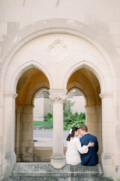 engaged couple sitting on a stone wall