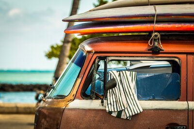 van with surf boards on top in front of the beach