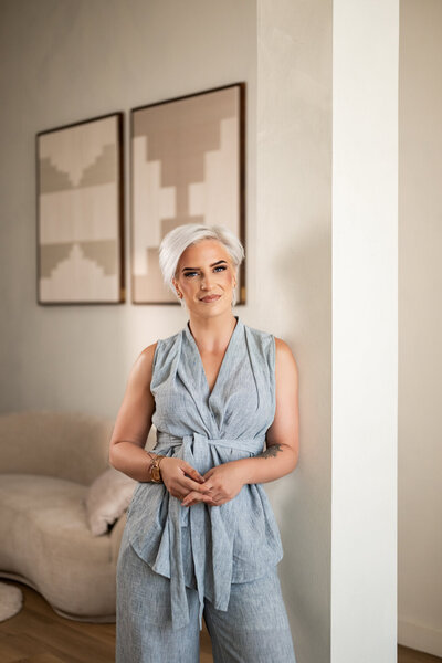 Brandingfoto in Studio Laurant: lachende vrouw met laptop in de hand, geposeerd bij de elegante bogen voor een professionele en stijlvolle uitstraling.