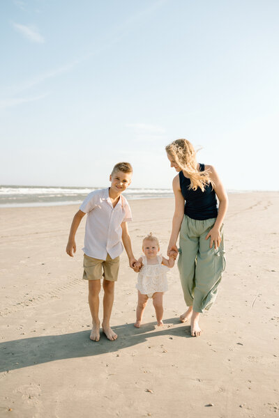 Family of three walking along Folly Beach during a Charleston sunrise photography session.