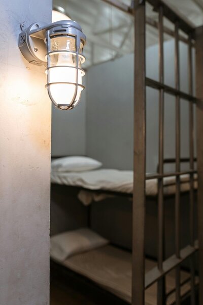 A man has his hands on a window looking down in despair in a prison cell