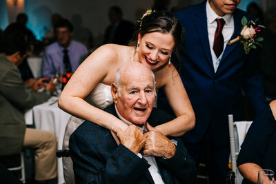 a bride hugging her grandfather during the reception of her wedding day in Massachusetts