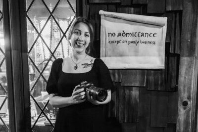 Connecticut wedding photographer standing with a sign, wearing a dress and holding a camera
