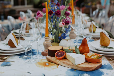 table with orange candles and fruit with white dishes