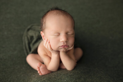 newborn sleeping on green blanket