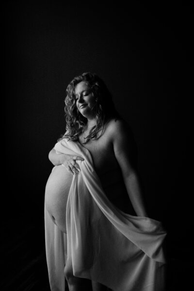 black and white image pregnant mother posing with sheet