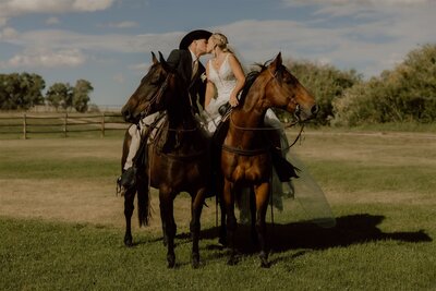 Outdoor wedding in Wyoming with a couple exchanging vows near their horses, surrounded by a rustic rural setting and natural light, creating a romantic and unique atmosphere.