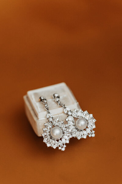 Wedding earrings with pearls in center on orange background