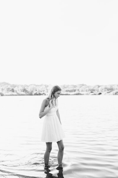 girl walking in lake water looking at it