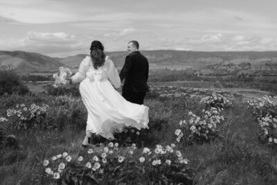 Bride & Groom in wedding attire frolicking through flowers in Oregon