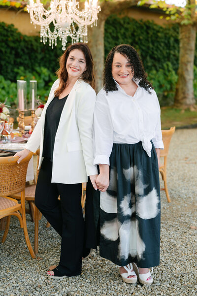 Italian wedding planning team  holding hands next to an reception dining table