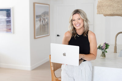 A warm and inviting image of Tara smiling while working on her laptop, embodying the friendly and supportive atmosphere of Connect Belong as she connects with women entrepreneurs.