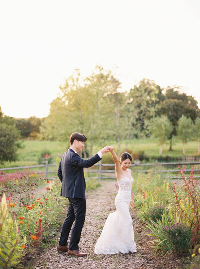 Bride and Groom pose in a field in the mountains, holding a bouquet of flowers