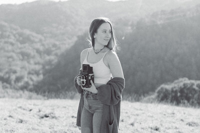 woman smiling and looking to the side while holding a camera