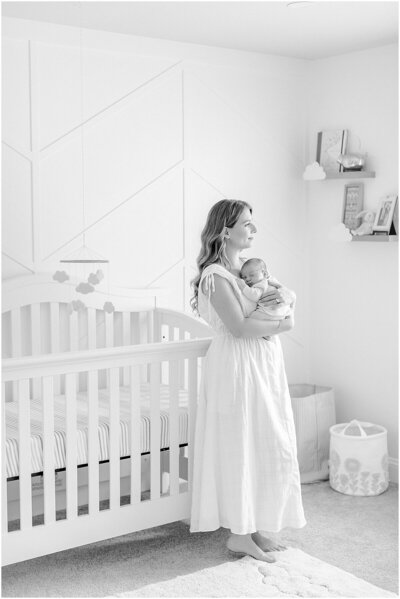 Mom holding baby in nursery during newborn photography session