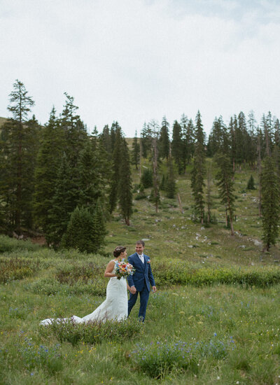 A couple walks into a field of wildflowers on their Colorado elopement