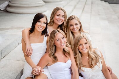 Five Vandy Kappa Kappa Gamma Seniors wearing white smiling at camera on the steps of Wyatt Center
