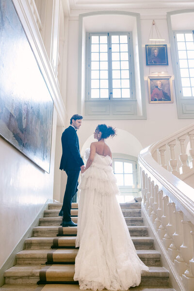 A groom leading his bride up the stairs in Chateau Du Grand Luce