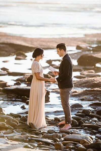 Elopement couple holds hands while facing each other and reading vows