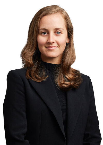 Confident woman in all black suit against a white background.