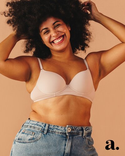 An image of a happy curvy woman with natural hair wearing eans.