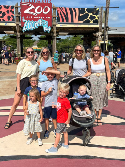 family poses in front of zoo