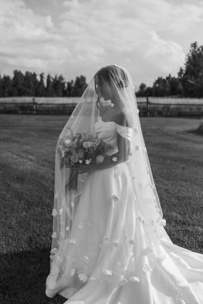 bride posing with a her wedding veil over her head with stunning floral showing through