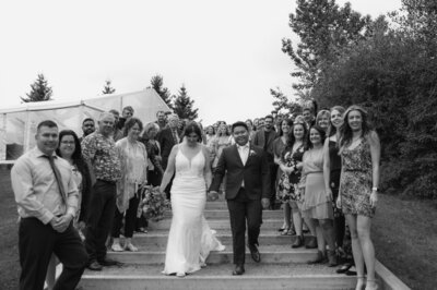 Couples exit on their wedding day black and white image of couples on the stairs with all family and friends behind them