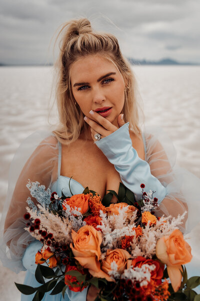 bride with bright peach and coral bouquet on the beach