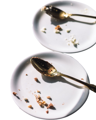 Two white plates with golden spoons and dessert crumbs left after enjoying pastries at Gold Leaf Pastries in Kamloops BC.