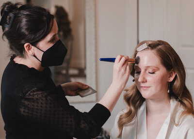 Kiley Smith a makeup artist is wearing a black top and applying makeup to a brides face in Middleburg Virginia