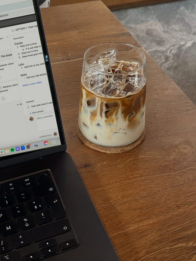 Woman grabbing pen at table with big notepad and mug