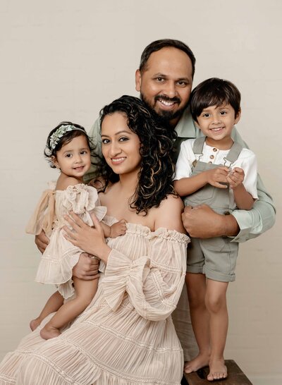 family of 4 taking a photo and smiling at the camera. Photo taken by Jenni Nikki Photography who services the Woodstock-Atlanta area. 