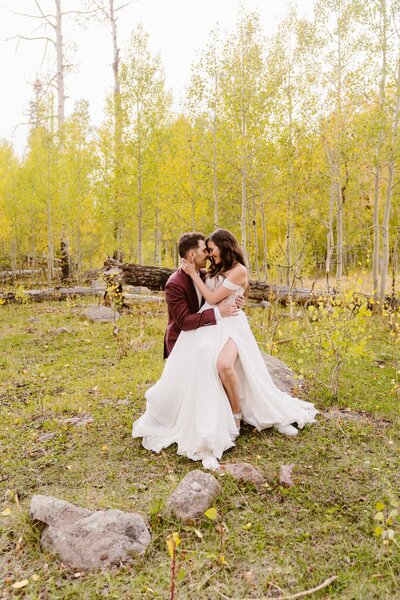 Couple embraces each other on a rock with yellow aspen trees in the background in Telluride, Colorado with Colorado wedding photographer Avenir Photo Co.