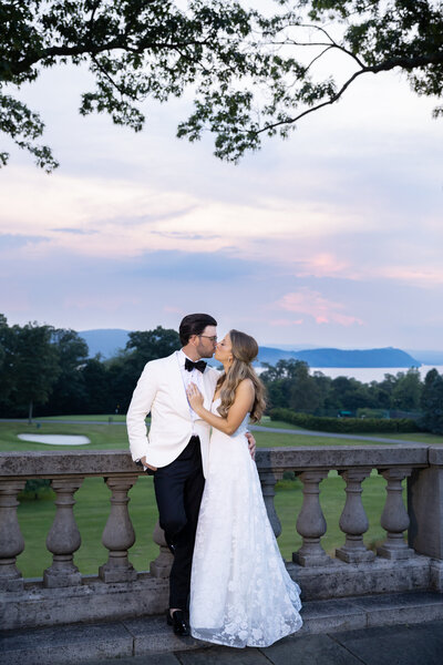 A bride and groom kiss outside of sleepy hollow country club at sunset