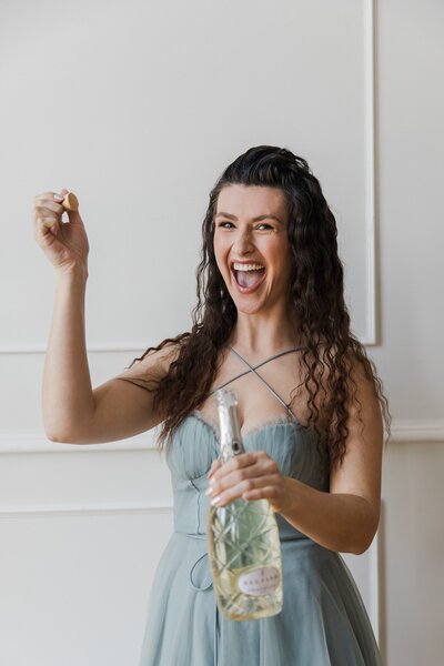 Hailey Ann Co Bookkeeper for female entrepreneurs popping champagne in professional headshot