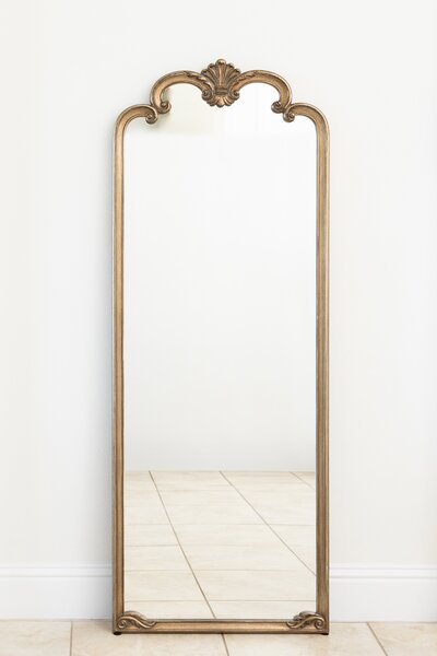 Gold oval mirror with ornate decorative top on black easel stand