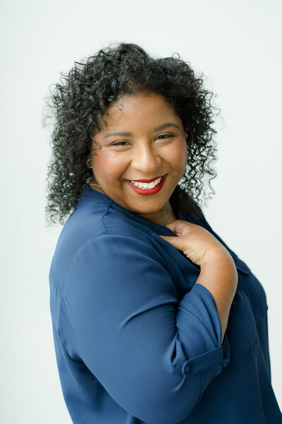 A warm and joyful portrait of Mica McCook, an Austin-based food photographer, smiling brightly while wearing a blue top. This image reflects Mica’s friendly and approachable personality, perfectly capturing her natural warmth.