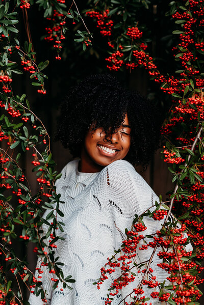 a beautiful black senior girl surrounded by holly smiling ear to wear