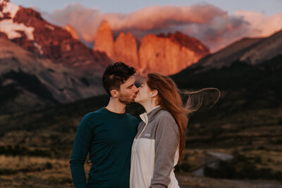 An eloping couple wearing a red dress and grey suit looks out  over Eibsee near Garmisch