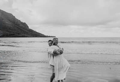 black and white image of couple of beach hugging