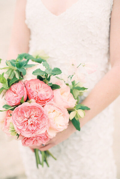 Bride wearing lace dress holding bouquet of pink florals