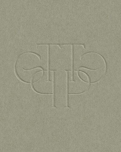 a green business card with an embossed monogram