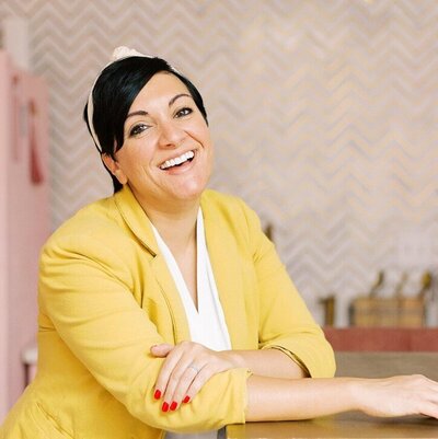 Client review showcasing success stories for a full-service Google Ads agency. The client is dressed in a yellow blazer and white blouse, highlighting their satisfaction and positive results.